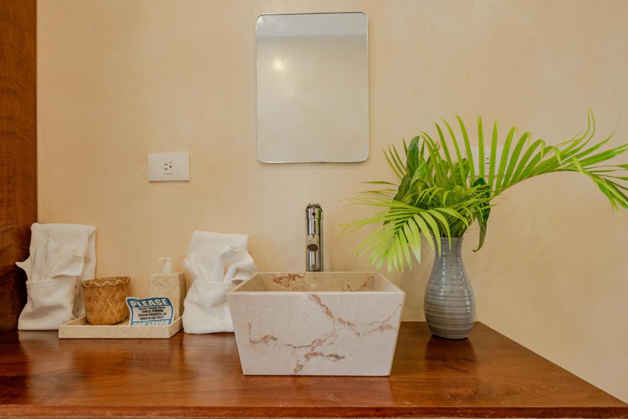 Baño de villa con lavabo de piedra tallada y planta tropical