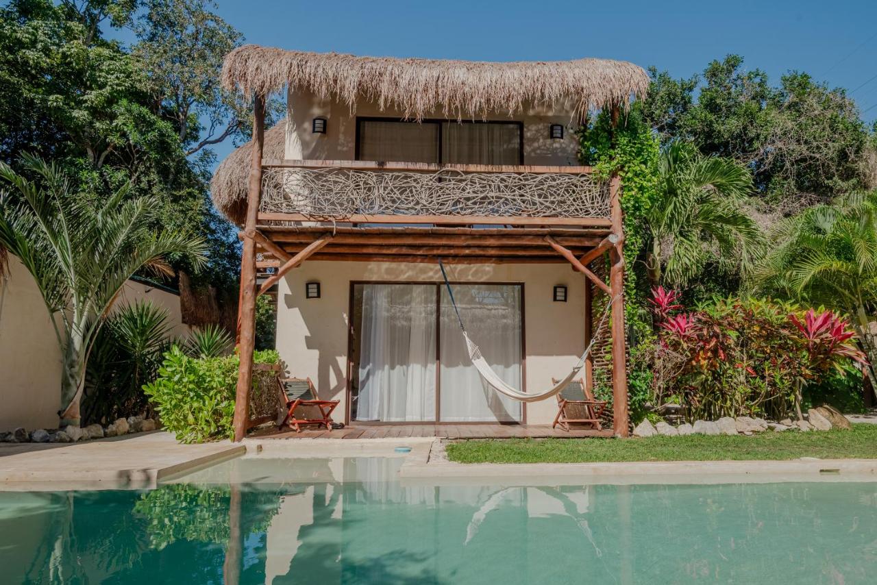 Bungalow de dos niveles con techo de palapa junto a la alberca